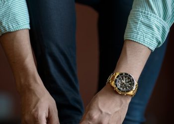 man tying his shoe laces while inside room during daytime