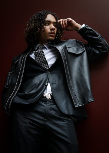 A man in a suit and tie leaning against a wall