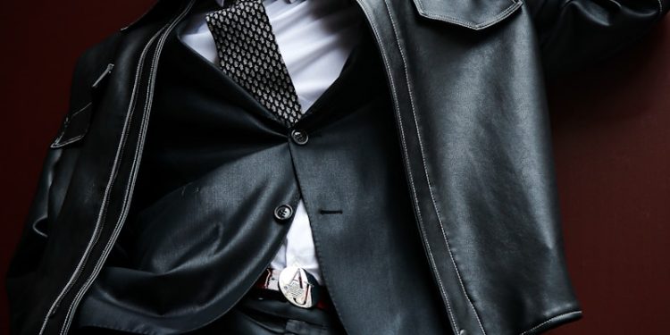 A man in a suit and tie leaning against a wall
