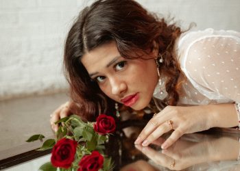 a woman holding a bouquet of roses in front of a mirror