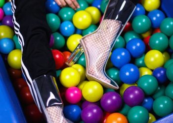 person sitting on assorted-color plastic ball lot