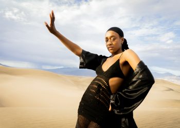 a woman in a black dress standing in the desert