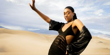 a woman in a black dress standing in the desert