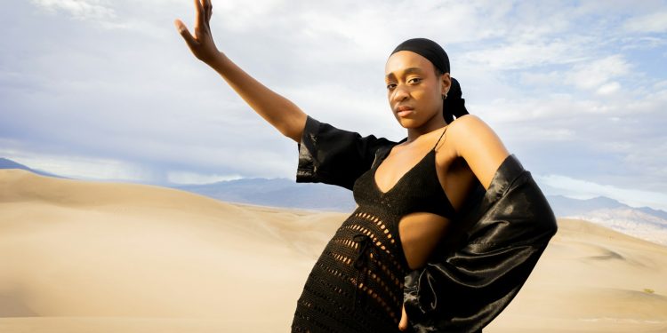 a woman in a black dress standing in the desert