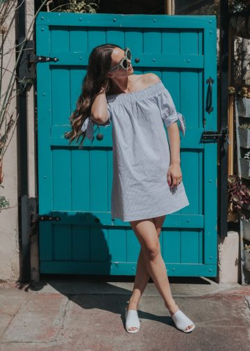 woman touching her hair standing near teal gate