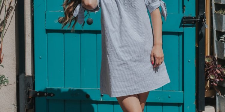 woman touching her hair standing near teal gate